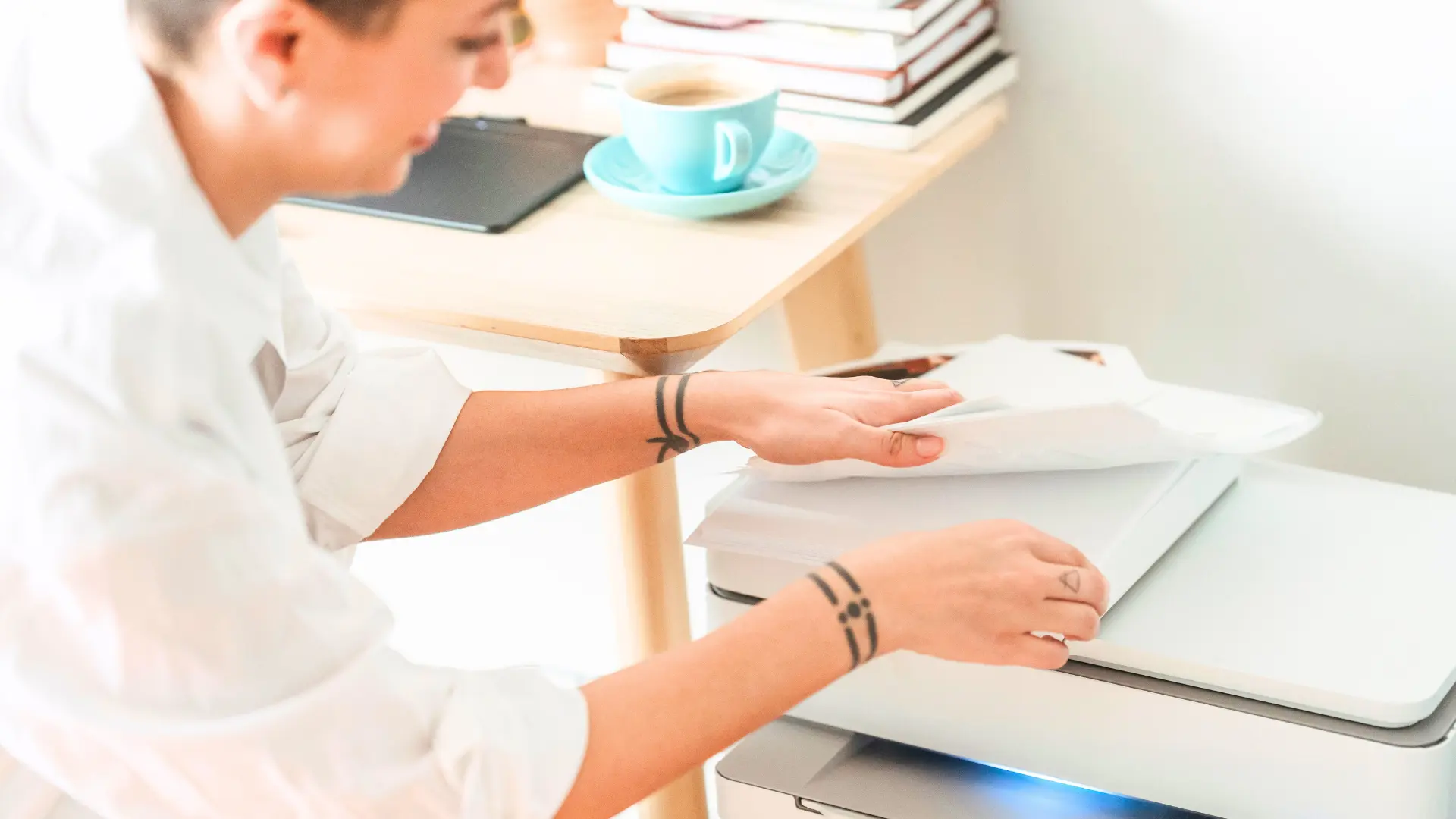 Frau mit Tattoos steht im Büro am Drucker